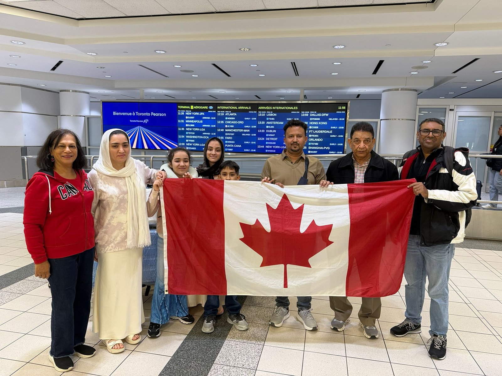 The Asad Durrani family holding the Canadian flag after arriving at Toronto Pearson, April 2026